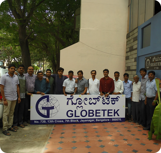 Group of employees standing outdoors holding a Globetek banner.