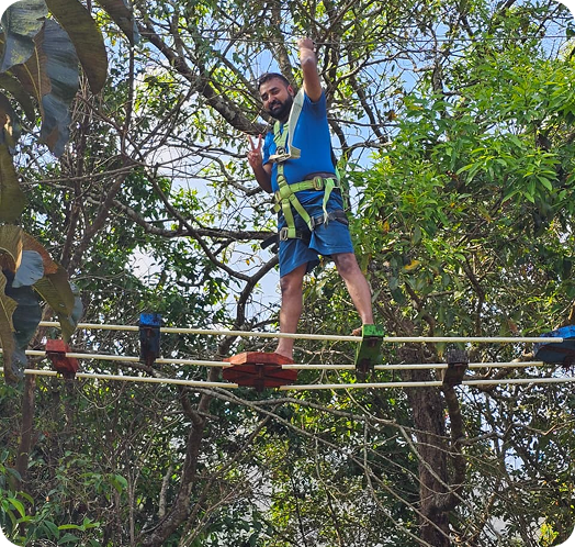 Person participating in a high ropes or zipline adventure course among trees.