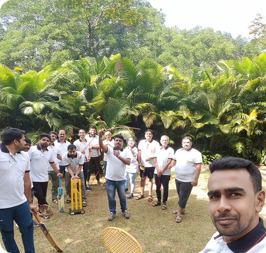 Group of employees enjoying an outdoor team-building activity in a garden with cricket equipment.